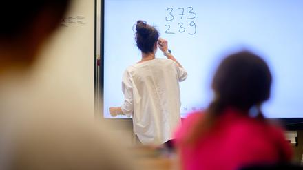 ARCHIV - 17.08.2023, Niedersachsen, Hannover: Eine Lehrerin schreibt eine Mathematikaufgabe auf eine digitale Schultafel im Klassenraum einer 4. Klasse einer Grundschule. (zu dpa: «Südwesten kann nach Pisa-Debakel mit neuem Mathe-Unterricht rechnen») Foto: Julian Stratenschulte/dpa +++ dpa-Bildfunk +++