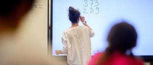 ARCHIV - 17.08.2023, Niedersachsen, Hannover: Eine Lehrerin schreibt eine Mathematikaufgabe auf eine digitale Schultafel im Klassenraum einer 4. Klasse einer Grundschule. (zu dpa: «Südwesten kann nach Pisa-Debakel mit neuem Mathe-Unterricht rechnen») Foto: Julian Stratenschulte/dpa +++ dpa-Bildfunk +++
