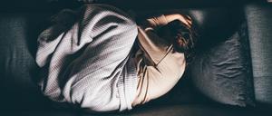 Eine Frau liegt erschöpft auf dem Bett