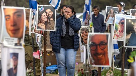 Eine Frau inmitten von Fotos von Hamas-Geiseln bei einer Veranstaltung auf dem Gelände des Supernova-Festivals. 