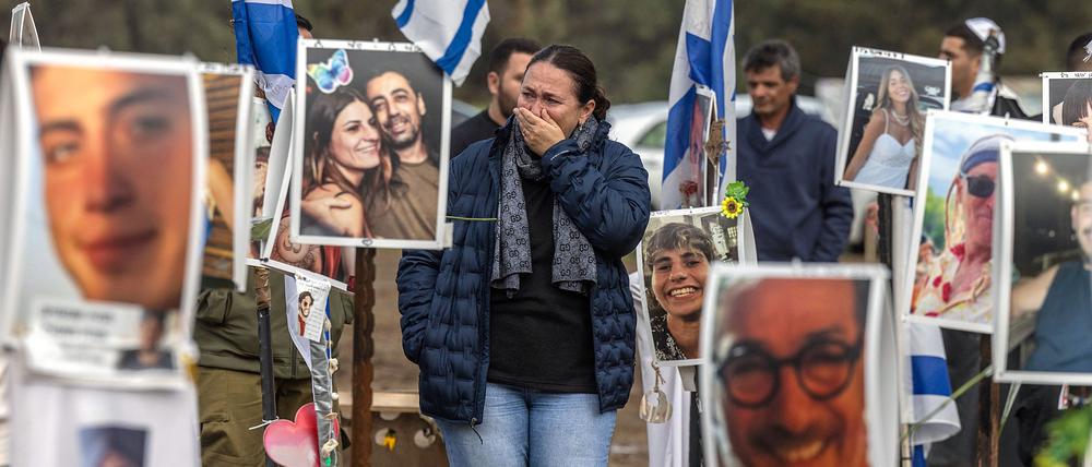 Eine Frau inmitten von Fotos von Hamas-Geiseln bei einer Veranstaltung auf dem Gelände des Supernova-Festivals. 