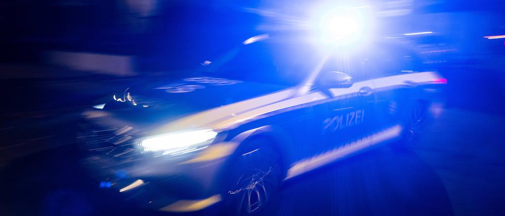 Ein Polizeifahrzeug fährt mit Blaulicht an einem Gebäude vorbei.