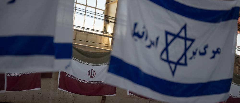 Iranische Flaggen und israelische mit der Aufschrift „Tod Israels“ hängen zum Trocknen in einer Fabrikhalle.