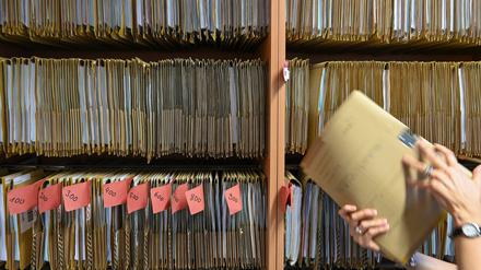 Eine Mitarbeiterin einer Behörde greift an einem Regal nach einer Akte. (Symbolbild)