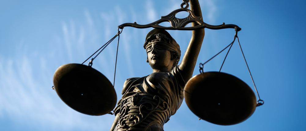 Eine Statue der Justitia hält eine Waage in der Hand.