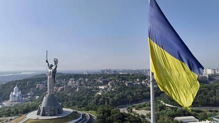 Das Mutterlandsdenkmal in Kiew aus der Luft. Im Vordergrund eine ukrainische Fahne.