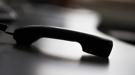 Ein Telefonhörer liegt auf einem Tisch. 