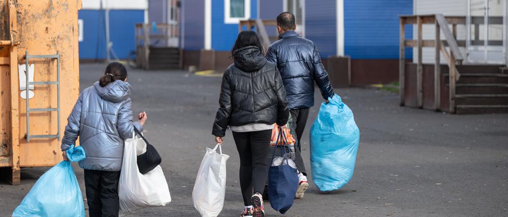 In Plastiksäcken tragen neu angekommene Flüchtlinge in Gießen ihre persönlichen Habseligkeiten zu ihrer Unterkunft in der Erstaufnahmeeinrichtung (Archivbild vom 22.11.2023).