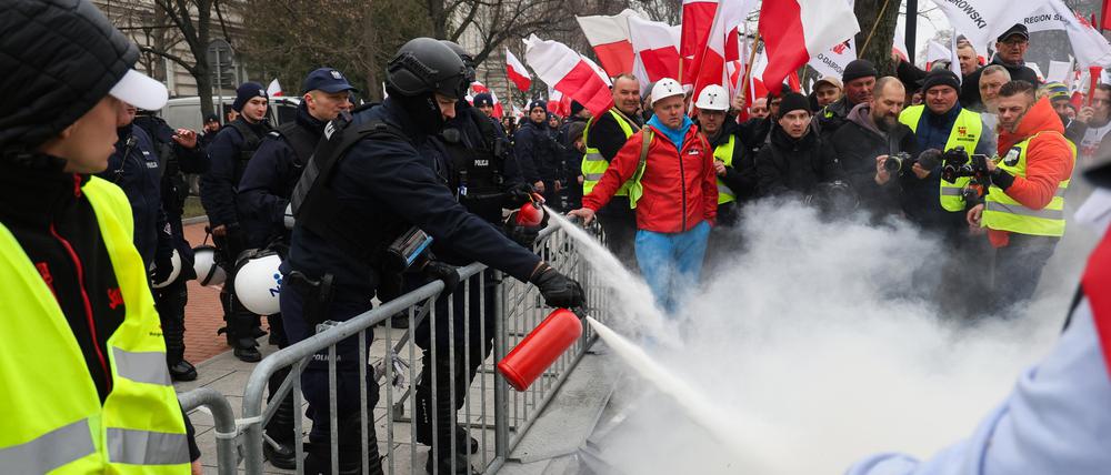 Polnische Einsatzkräfte löschen brennende Reifen, die von Landwirten während der Proteste in Warschau angezündet wurden.