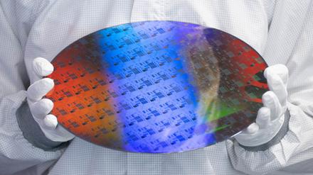 Ein Mitarbeiter eines Chip-Herstellers hält einen Wafer –  das ist das Ausgangsmaterial für die Chipproduktion. 