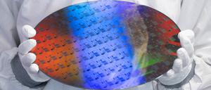 Ein Mitarbeiter des Chip-Herstellers Globalfoundries hält einen Wafer - bearbeitetes Halbleiterausgangsmaterial für die Chipproduktion in der Halbleitertechnologie.