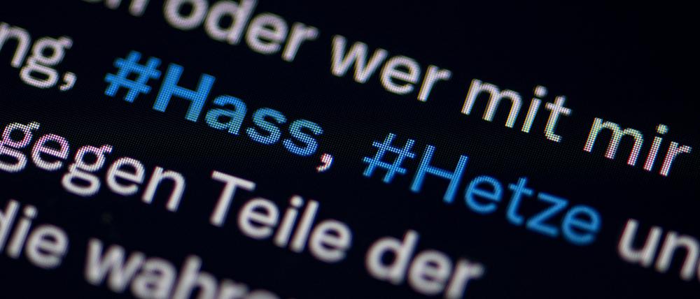 Auf dem Bildschirm eines Smartphones sieht man die Hashtags Hass und Hetze in einem Twitter-Post.