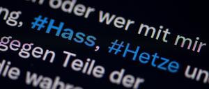 Auf dem Bildschirm eines Smartphones sieht man die Hashtags Hass und Hetze in einem Twitter-Post.