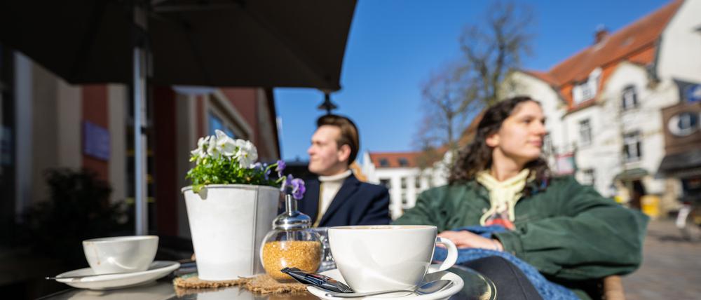 08.03.2024, Nordrhein-Westfalen, Telgte: Ein junges Pärchen genießt bei strahlendem Sonnenschein eine Tasse Kaffee im Außenbereich eines Cafes.
