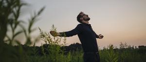 Ein Mann in der Natur atmet durch, ein Bild der Hoffnung und Befreiung.