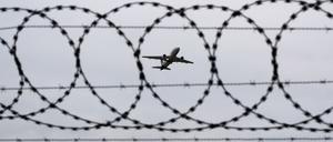 Ein Flugzeug startet am Flughafen – fotografiert durch Stacheldraht am Flughafenzaun. (Symbolbild)