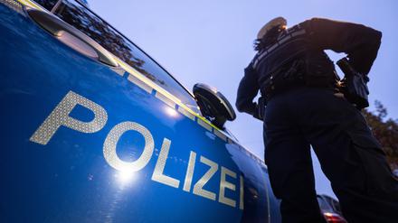  Eine Polizistin steht neben einem Polizeifahrzeug. 