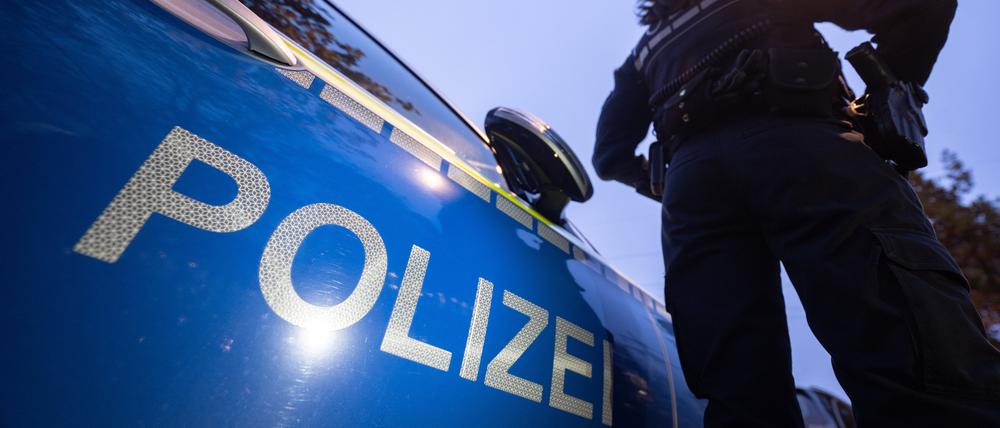  Eine Polizistin steht neben einem Polizeifahrzeug. 