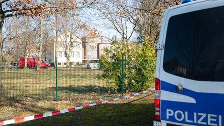 Ein Polizeiauto steht vor einer Schule. 