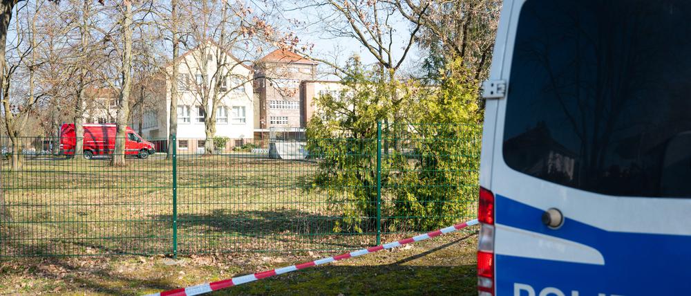 Ein Polizeiauto steht vor einer Schule. 
