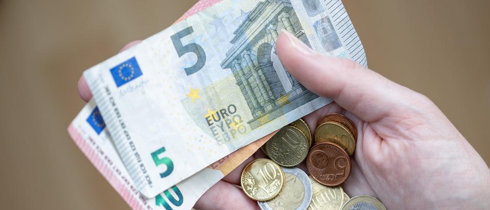 Eine Frau hält Geldscheine und Münzen in der Hand. (Symbolbild)