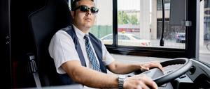 Ein Busfahrer mit Sonnenbrille am Steuer.