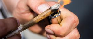 Eine Person zündet einen Joint an. (Symbolbild)