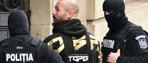 Der umstrittene Influencer Andrew Tate wird am 12. März 2024 von Polizeibeamten in das Gebäude des Berufungsgerichts in Bukarest (Rumänien) geführt.