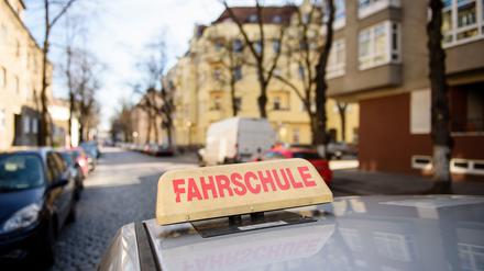 Ein Schild mit der Aufschrift „Fahrschule“ ist auf dem Dach eines Fahrschulwagens montiert. 