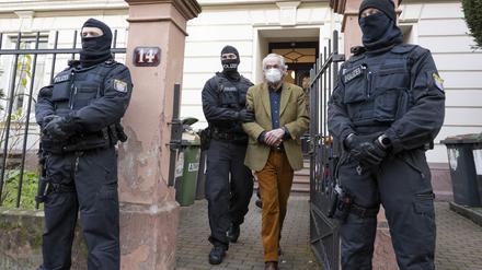 Bei einer Razzia 2022 führten vermummte Polizisten Heinrich XIII Prinz Reuß (2.v.r.) zu einem Polizeifahrzeug.