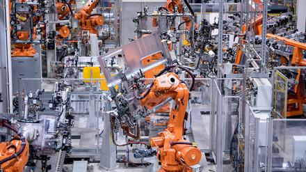 Bayern, München: Roboter von ABB arbeiten bei MAN Truck & Bus in einer Werkshalle an Seitenwänden von Fahrerkabinen von Lastwagen. 