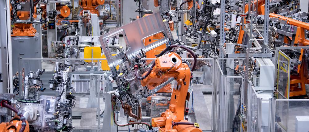 Bayern, München: Roboter von ABB arbeiten bei MAN Truck & Bus in einer Werkshalle an Seitenwänden von Fahrerkabinen von Lastwagen. 