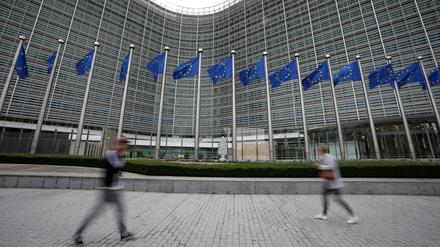 Die Flaggen der Europäischen Union wehen im Wind, während Fußgänger an der Zentrale der EU-Kommission vorbeigehen.