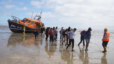 Eine Gruppe von Menschen, bei denen es sich vermutlich um Migranten handelt, wird von einem Rettungsboot nach einem Zwischenfall mit einem kleinen Boot im Ärmelkanal an Land gebracht.  