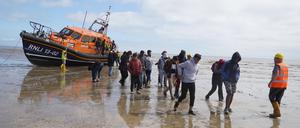 Eine Gruppe von Menschen, bei denen es sich vermutlich um Migranten handelt, wird von einem Rettungsboot nach einem Zwischenfall mit einem kleinen Boot im Ärmelkanal an Land gebracht.  