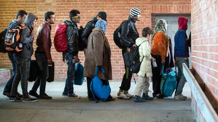 Flüchtlinge, die zuvor mit einem Sonderzug angekommen waren, warten am 03.10.2015 am Bahnhof in Schönefeld (Brandenburg), auf ihre Weiterfahrt zur Unterkunft mit Bussen.