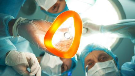 Ein Ärzteteam steht um einen Patienten herum. Ein Arzt hält eine Narkosemaske in der Hand.