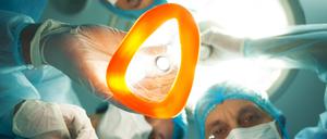 Ein Ärzteteam steht um einen Patienten herum. Ein Arzt hält eine Narkosemaske in der Hand.