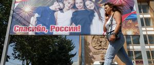 Eine Frau geht an einem Plakat vorbei, auf dem das 15-jährige Jubiläum der Anerkennung der Unabhängigkeit Südossetiens durch Russland gefeiert wird (Archivbild vom 21. August 2023).
