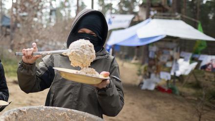 dpatopbilder - 17.03.2024, Brandenburg, Grünheide: Ein Aktivist nimmt sich in einem Camp der Initiative «Tesla stoppen» in einem Kiefernwald nahe der Tesla-Gigafactory Berlin-Brandenburg eine Portion Porridge. Ziel der Aktivisten ist es, eine Rodung des Waldstücks im Zuge einer geplanten Erweiterung des Tesla-Geländes mit Güterbahnhof zu verhindern. Foto: Sebastian Christoph Gollnow/dpa +++ dpa-Bildfunk +++