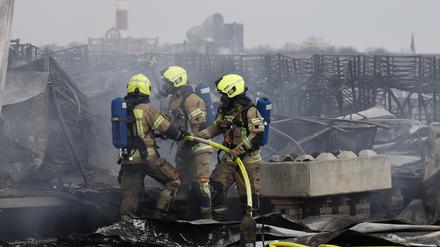 Die Feuerwehr löscht die Brandstelle bei Flüchtlingsunterkunft am ehemaligen Flughafen Tegel.