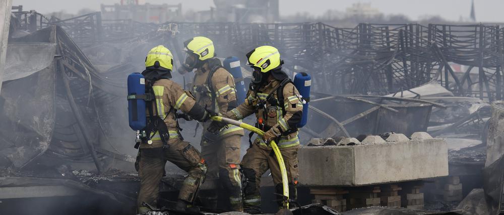 Die Feuerwehr löscht die Brandstelle bei Flüchtlingsunterkunft am ehemaligen Flughafen Tegel.
