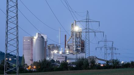 Strommasten stehen im Morgenlicht vor einem Zementwerk in Baden-Württemberg. 
