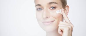 Frau trägt sich Gesichtscreme auf.