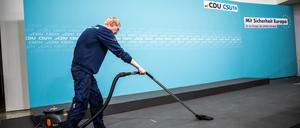 Wer wenig verdient, kann aufstocken. Hier will die CDU Neuerungen. Ein Gebäudereiniger saugt das Podium vor einer gemeinsamen Pressekonferenz von CDU und CSU.