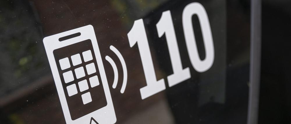 Der Notruf der Polizei (110) klebt an einem Polizeiwagen.