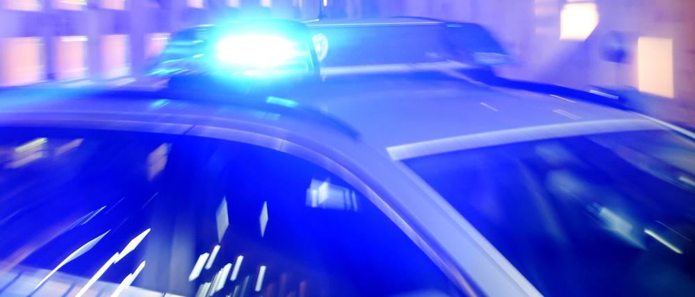 Ein Streifenwagen der Polizei steht mit eingeschaltetem Blaulicht auf der Straße. 