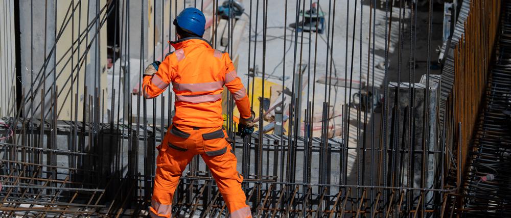 Ein Bauarbeiter verlegt auf einer Baustelle Stahlmatten.