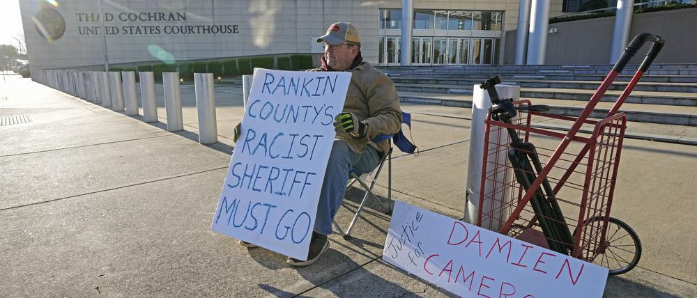 62, aus Jackson, sitzt vor dem Thad Cochran United States Courthouse in mit Plakaten Unterstützung für die beiden Männer, die von damals Vollzugsbeamten des Mississippi Rankin County misshandelt wurden.