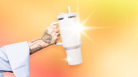 Tätowierte Hand hält einen Stanley-“Quencher“.